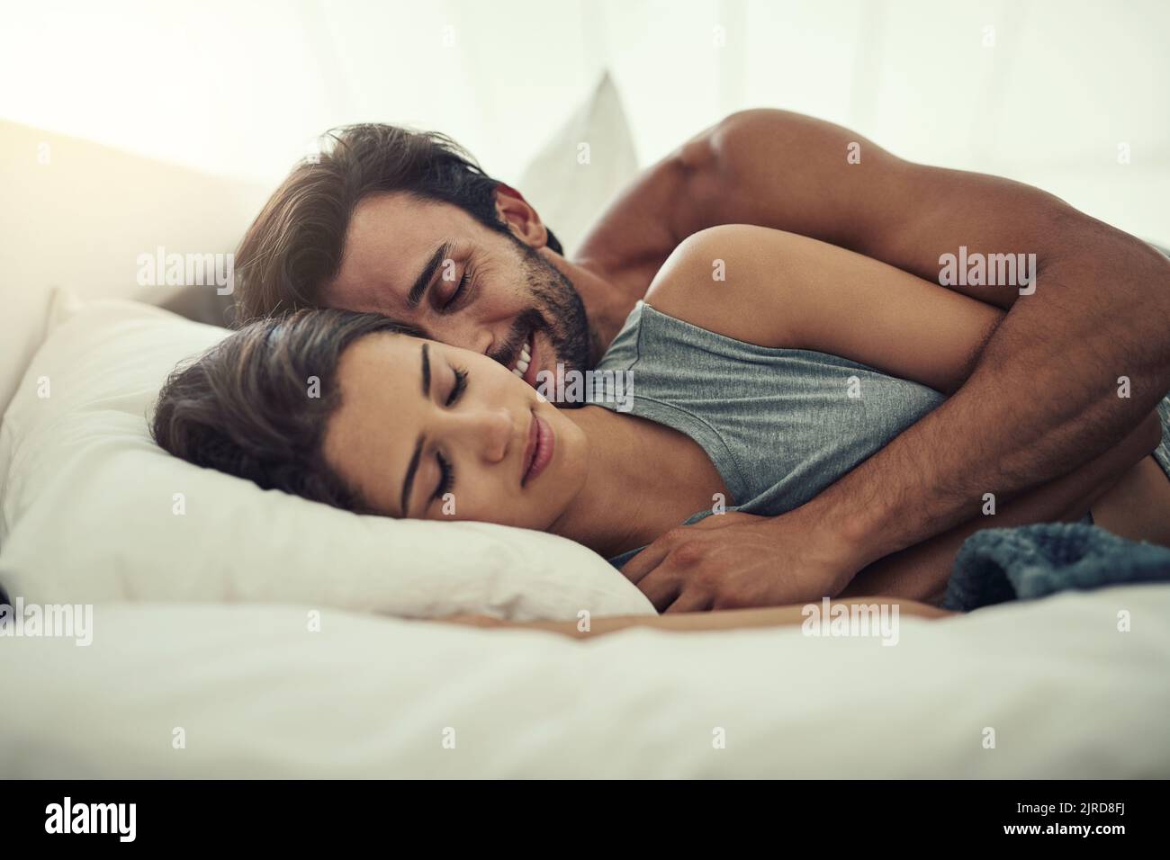 Even asleep theyre in love. an affectionate young couple sleeping in their bed. Stock Photo