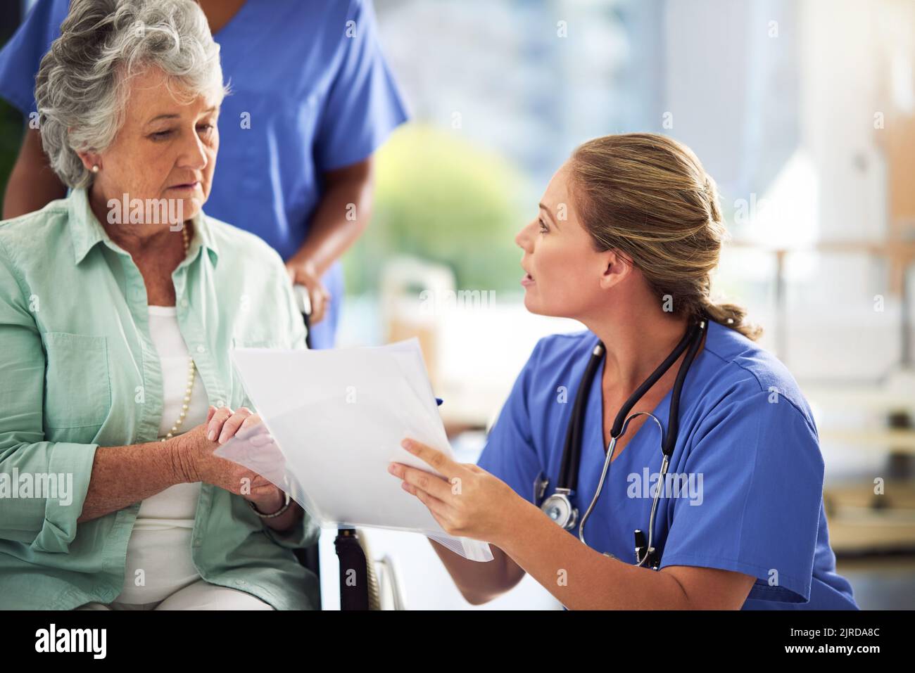 Treatments explained in plain English. a doctor discussing treatments with a senior woman sitting in wheelchair in a hospital. Stock Photo