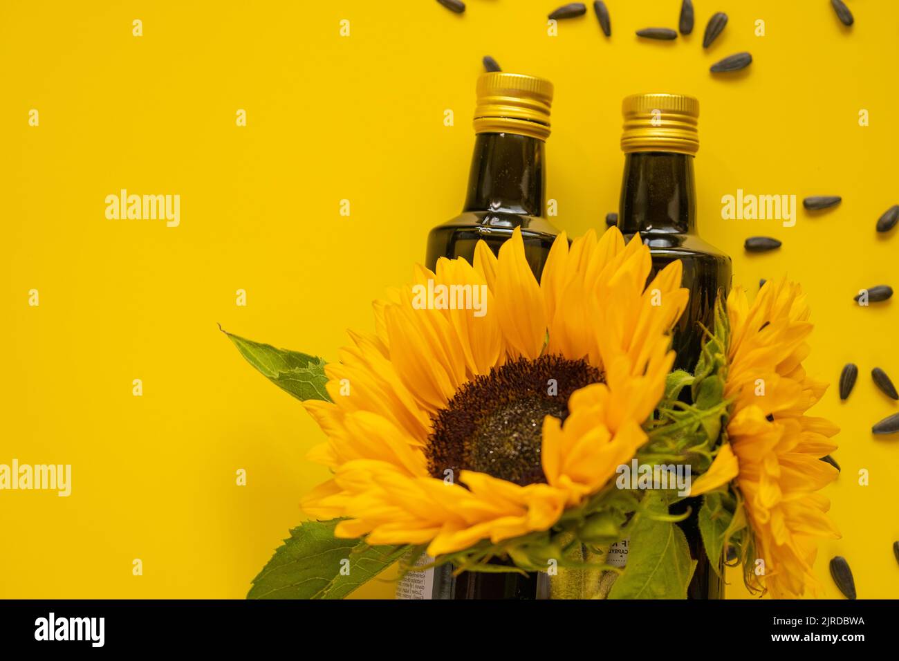 Sunflower Oil bottles, scattered black sunflower seeds and sunflowers