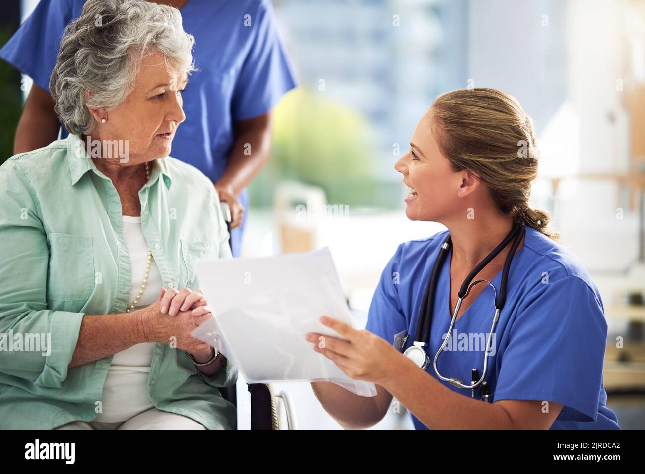 Keeping her patients in the loop. a doctor discussing treatments with a senior woman sitting in wheelchair in a hospital. Stock Photo