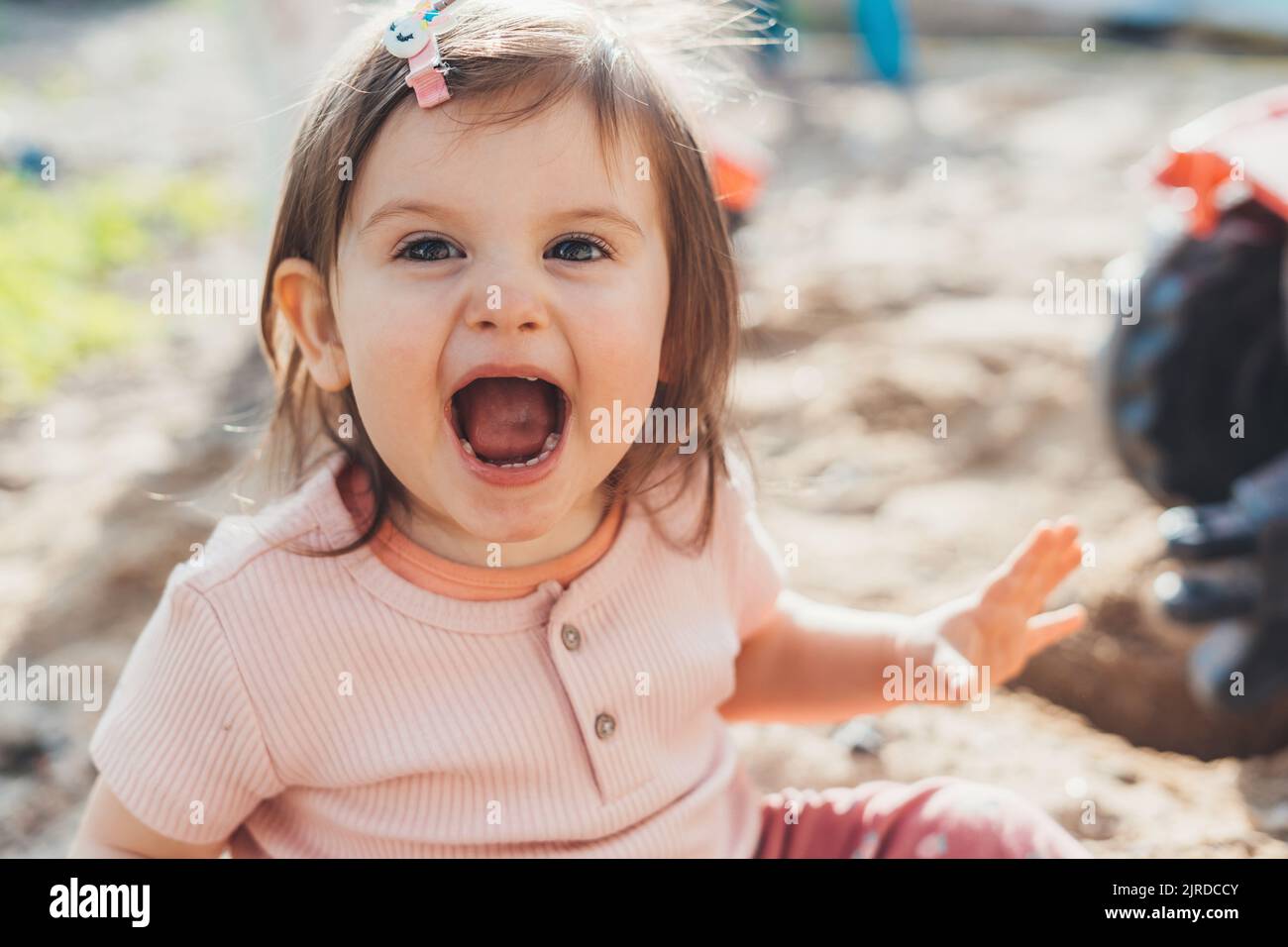 Overjoyed baby girl playing sand box at home backyard. Baby development
