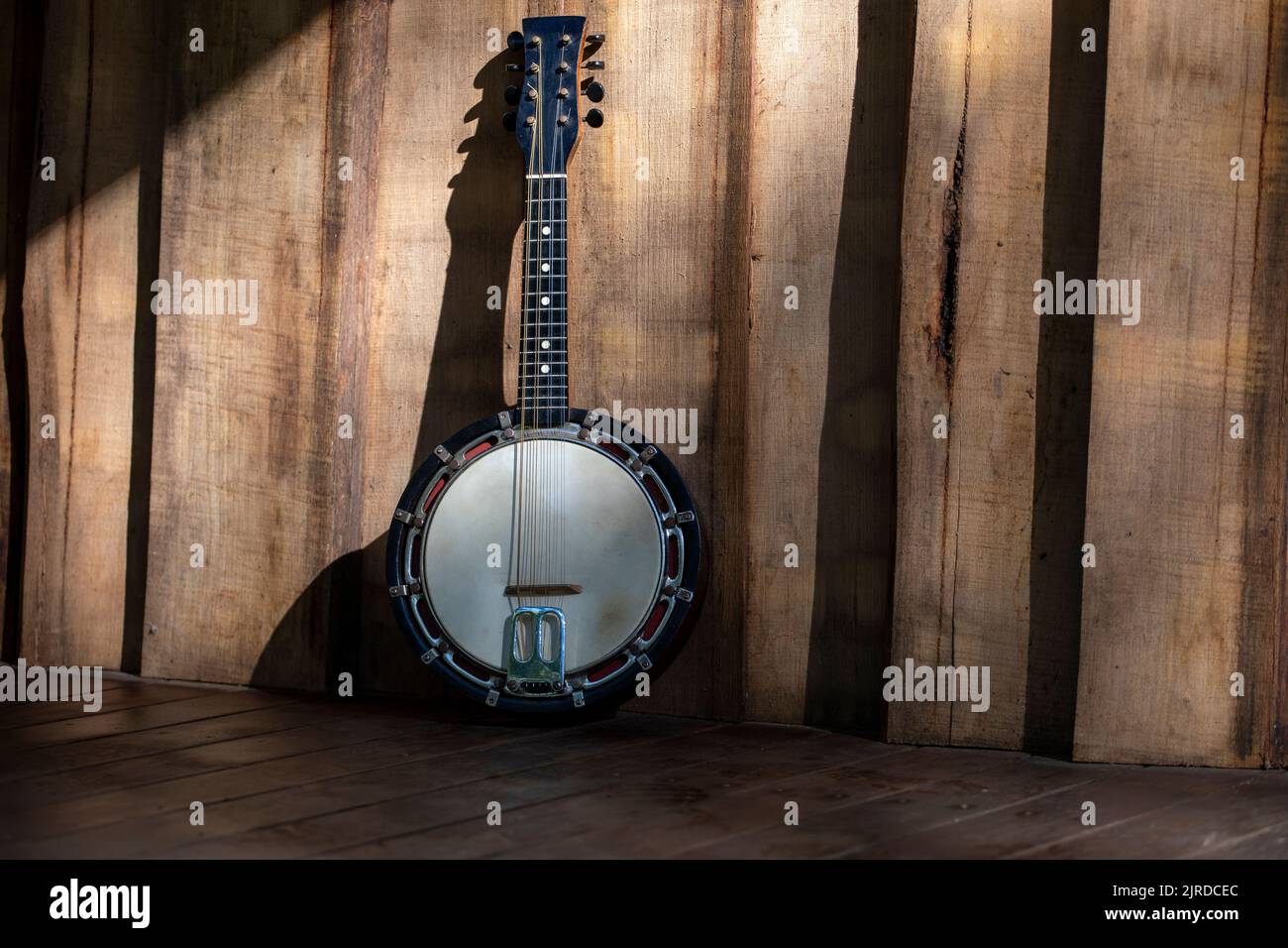 Banjo mandolin leaning against raw vertical wooden cladding, with Copy space. Stock Photo