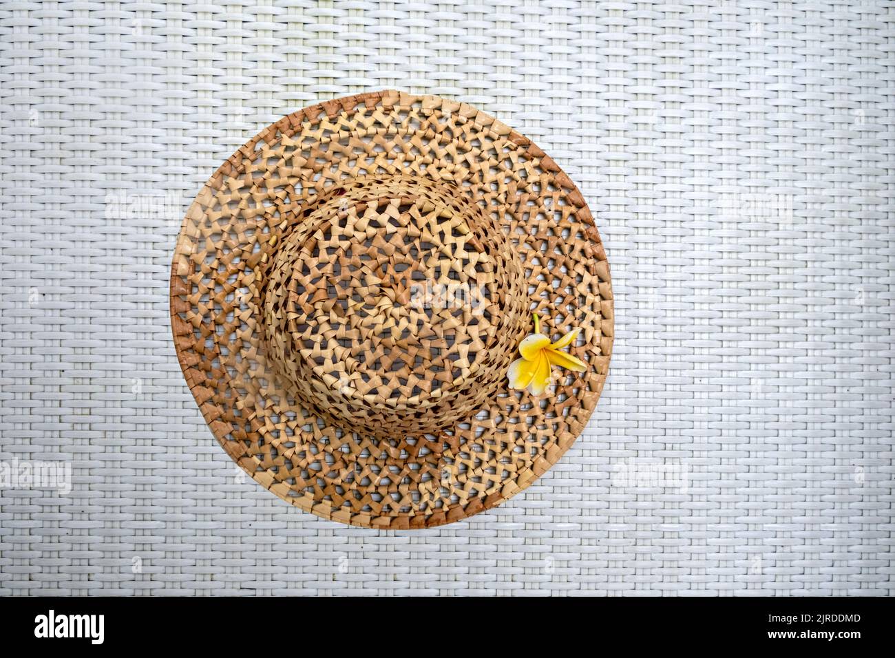 Travel.. Summer mockup. Straw hat on a white textured background with a frangipani flower. View from above. The concept of holidays, vacations and Stock Photo