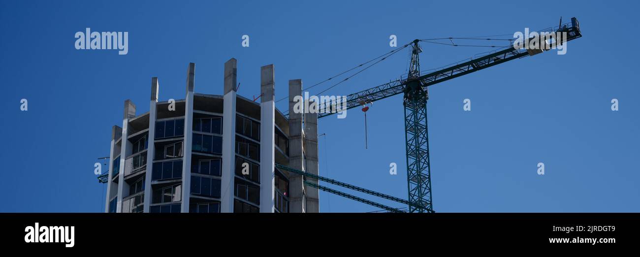 Construction crane standing near modern building against blue sky Stock ...