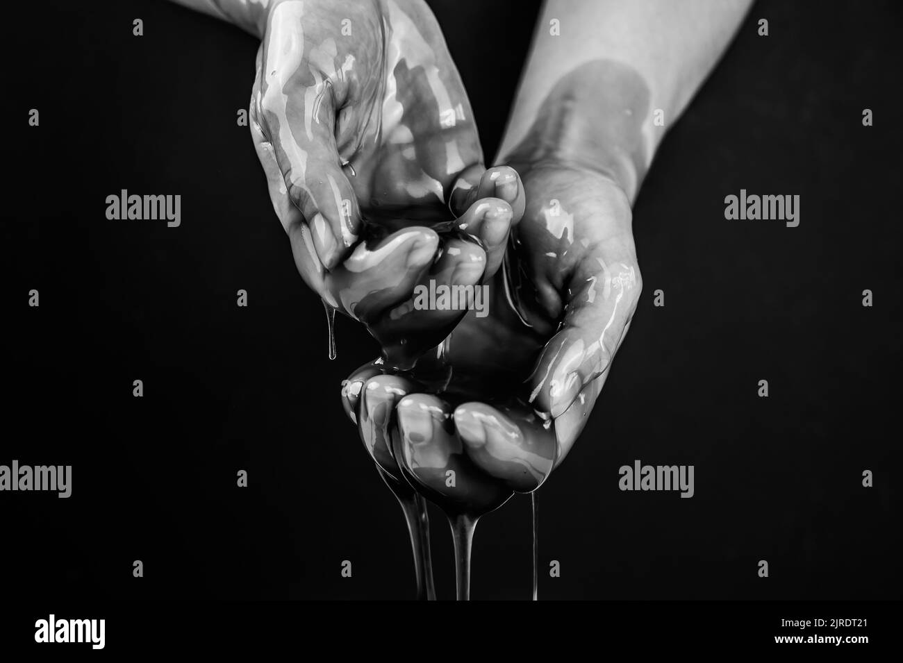 Women's hands in a viscous liquid similar to blood. Black and white