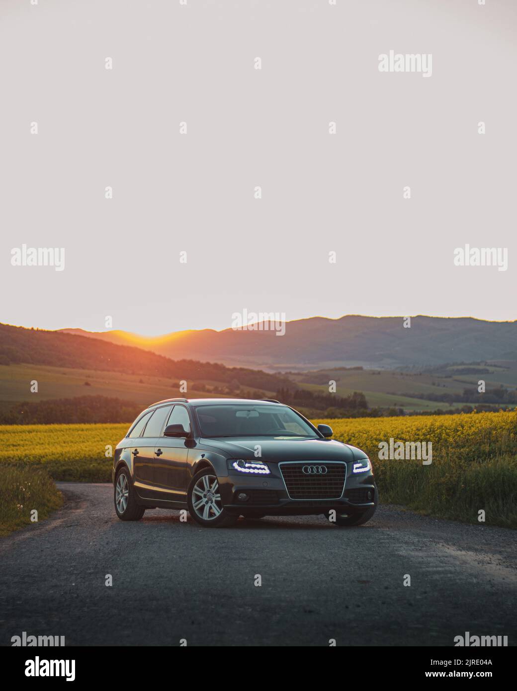 A vertical shot of an Audi A4 on a rural road at sunset Stock Photo