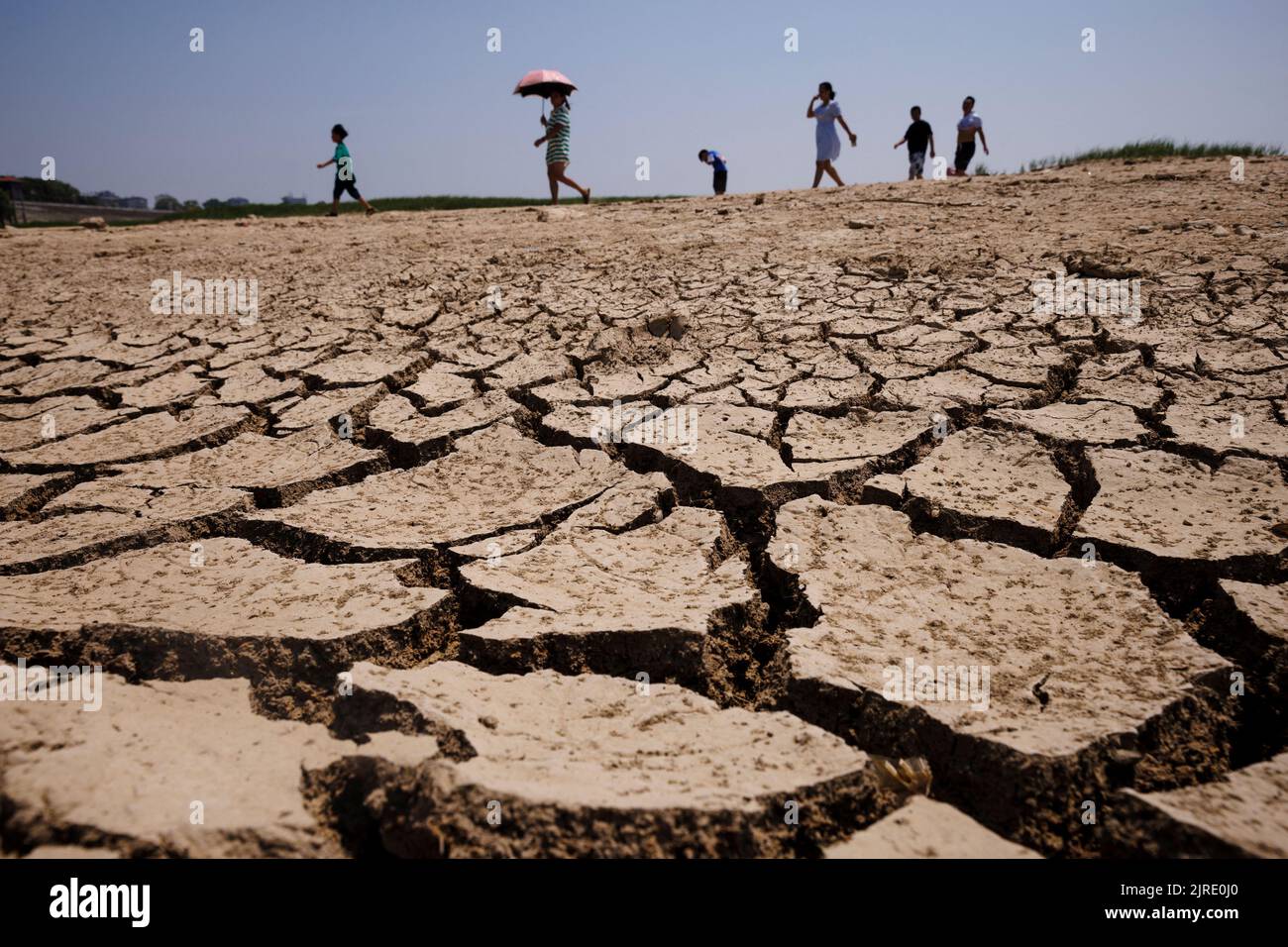 People walk across a dried-up section of Poyang Lake that is facing low water levels due to a regional drought in Lushan, Jiangxi province, China, August 24, 2022.  REUTERS/Thomas Peter Stock Photo