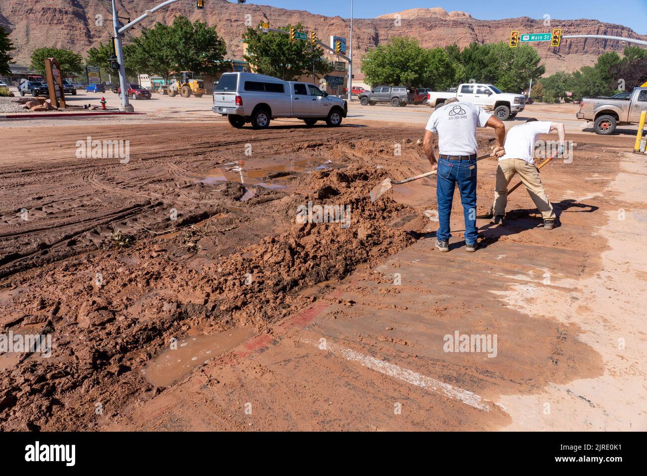 Volunteers shovel mud from the front of a local business the day after
