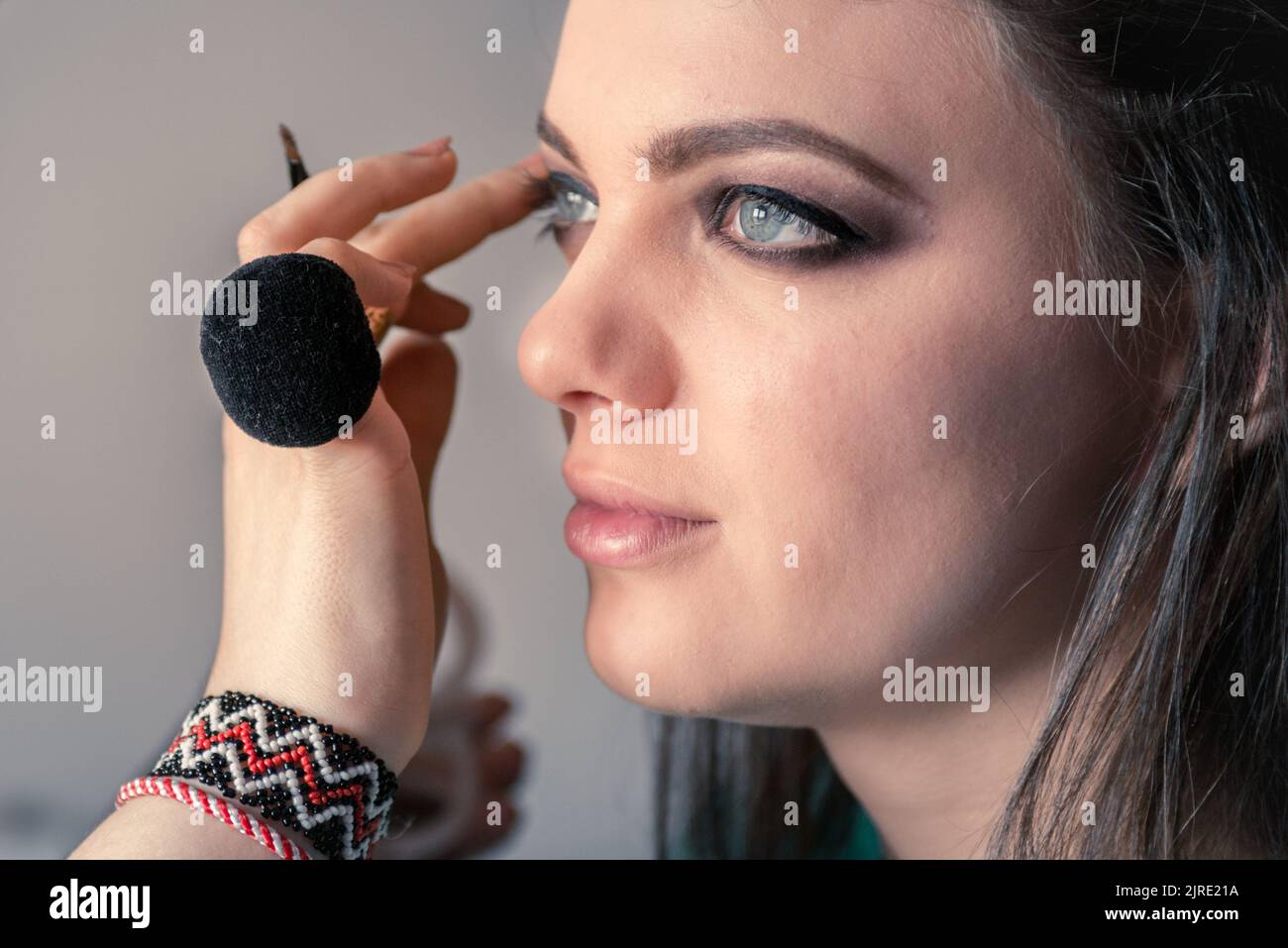 The makeup artist has on her finger a black powder puff and she is