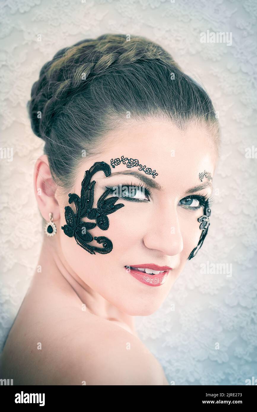 Young female model with braided blonde hair, big green eyes and decorative  black lace on her face, smiling, on white lace background Stock Photo -  Alamy