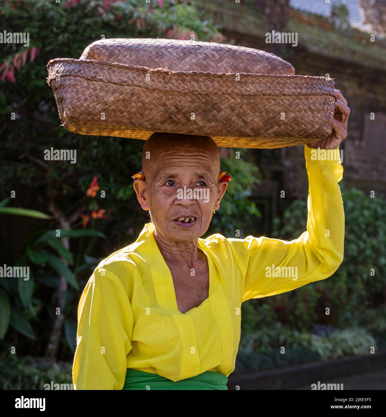 Woman carries basket on her head as she walks Stock Photo - Alamy