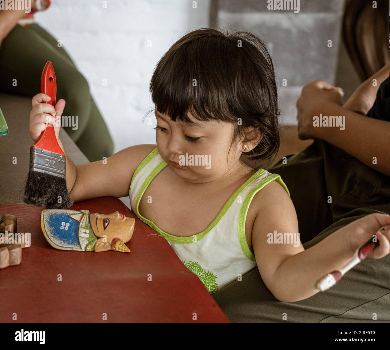 Child learns to create statue and apply final lacquer Stock Photo Alamy
