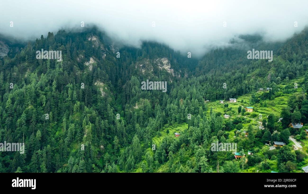 beautiful aerial landscape of moody rain clouds rolling over the mountain peaks in Jibhi covered in cedar trees Stock Photo
