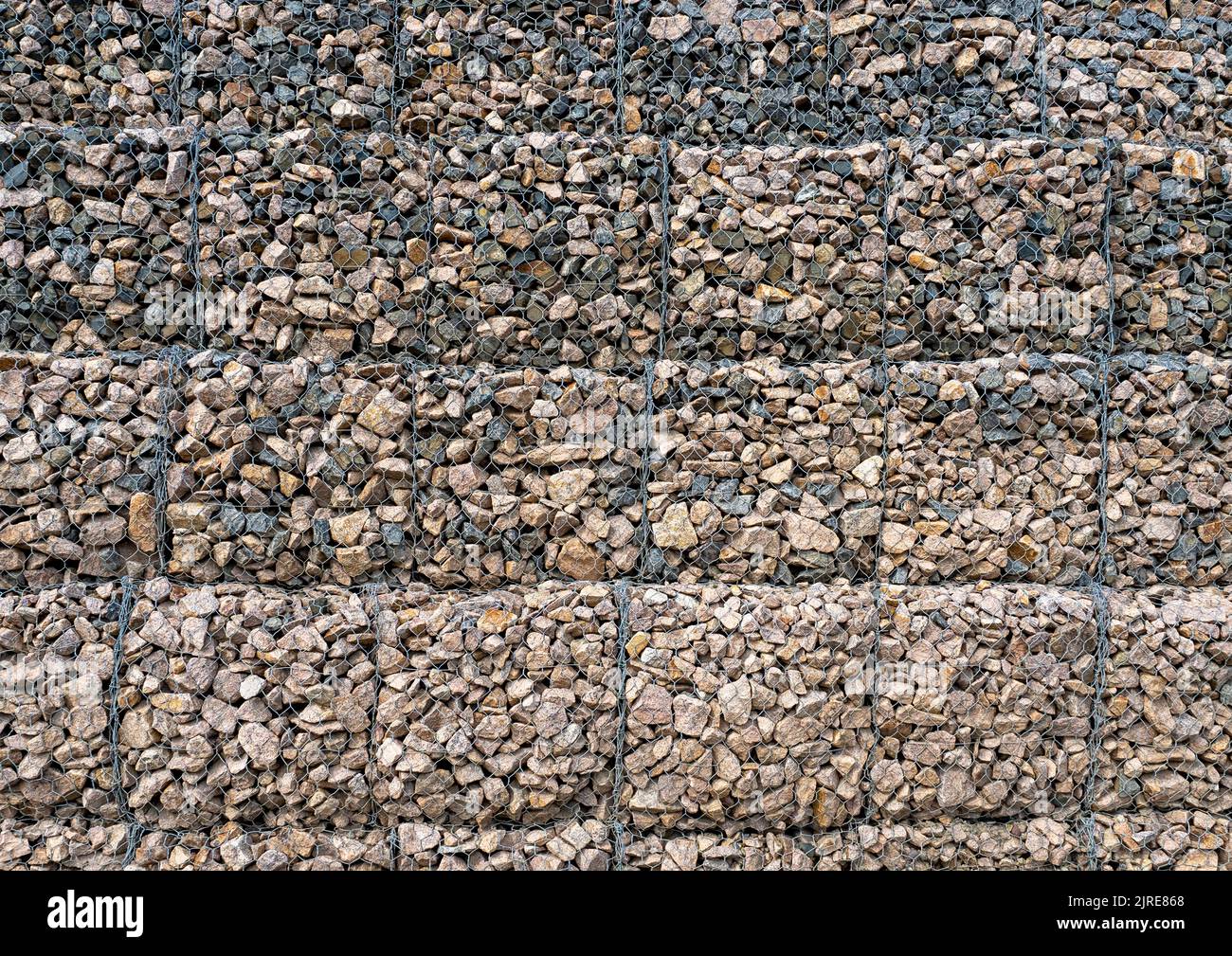 Gabion with heaps of small stones in a grid as the city or garden decoration, textured background Stock Photo