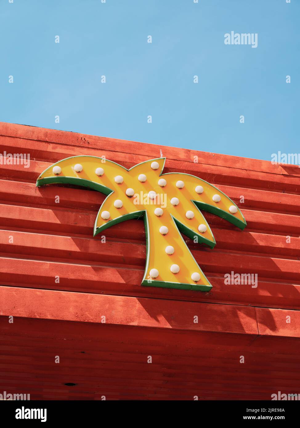 A yellow palm tree light sign on the colourful shops cafes and ...