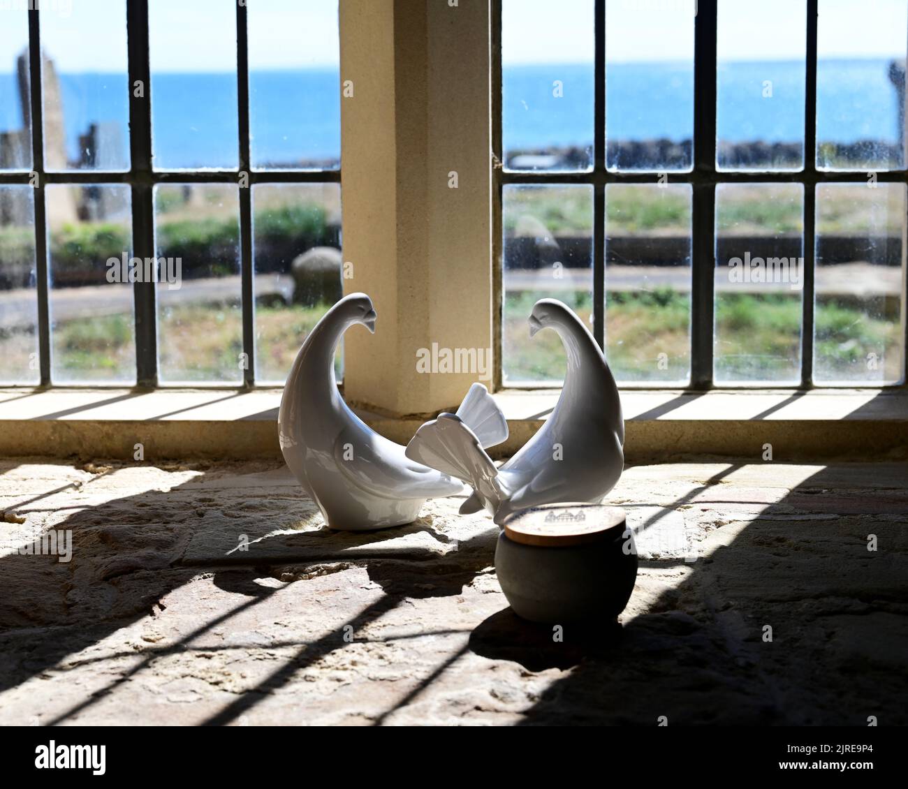 Pair of ceramic white china fan tailed doves framed in an old 13th century church window Stock Photo