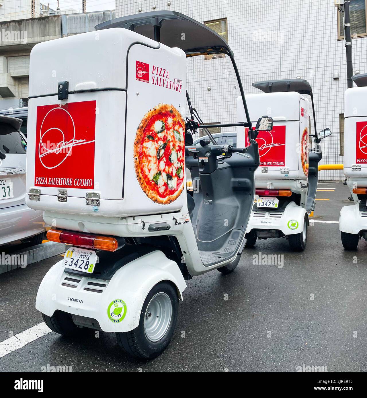 A rear picture of Three 3 Wheel Mobility Scooter Balance Delivery Motorcycles for pizza Salvatore with Roofs parked in a parking lot. Stock Photo