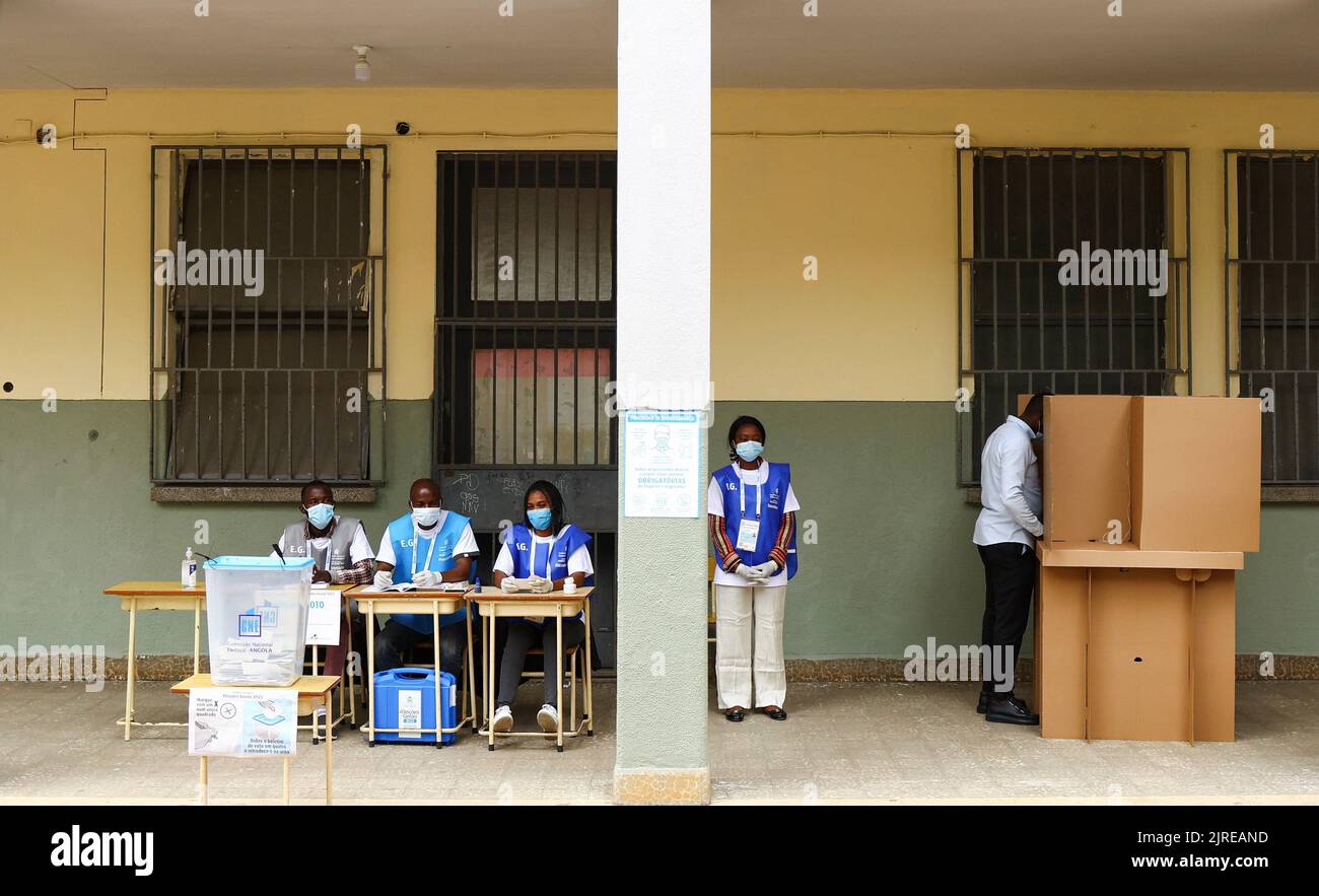 Election officials look on as a man casts his vote during the general election at Nzinga Mbandi school in the capital Luanda, Angola August 24, 2022. REUTERS/Siphiwe Sibeko Stock Photo