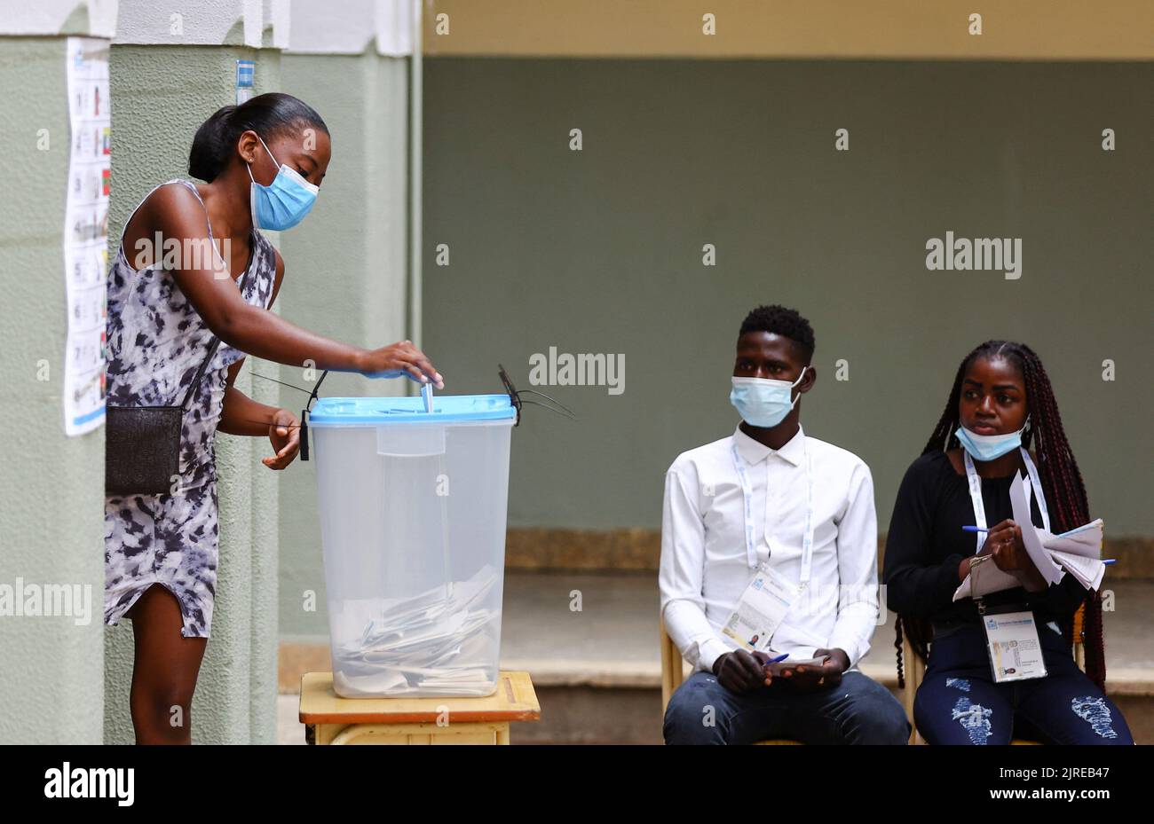 A woman casts her vote while election officials look on during the general election at Nzinga Mbandi school in the capital Luanda, Angola August 24, 2022. REUTERS/Siphiwe Sibeko Stock Photo
