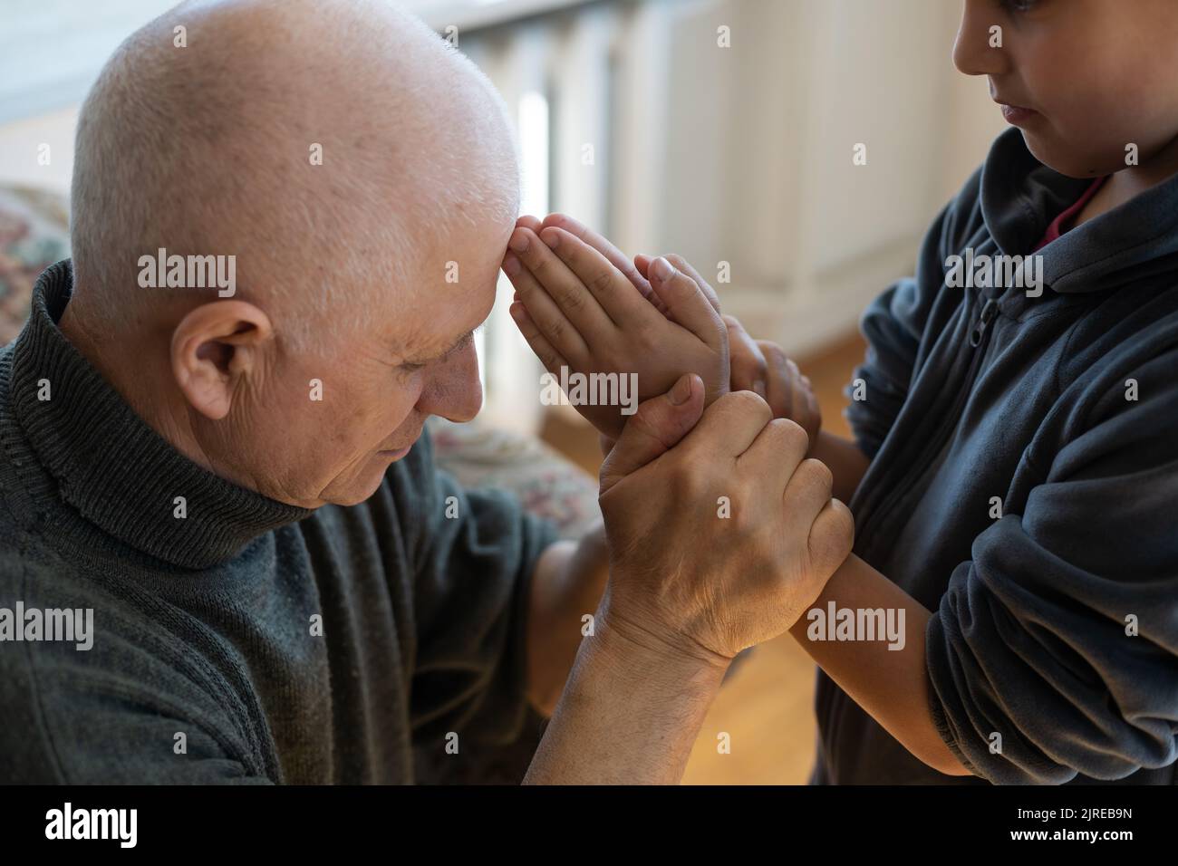 A hand of a granddaughter is holding a wrinkled hand of an old man symbolizing care, attention and unconditional love. Stock Photo