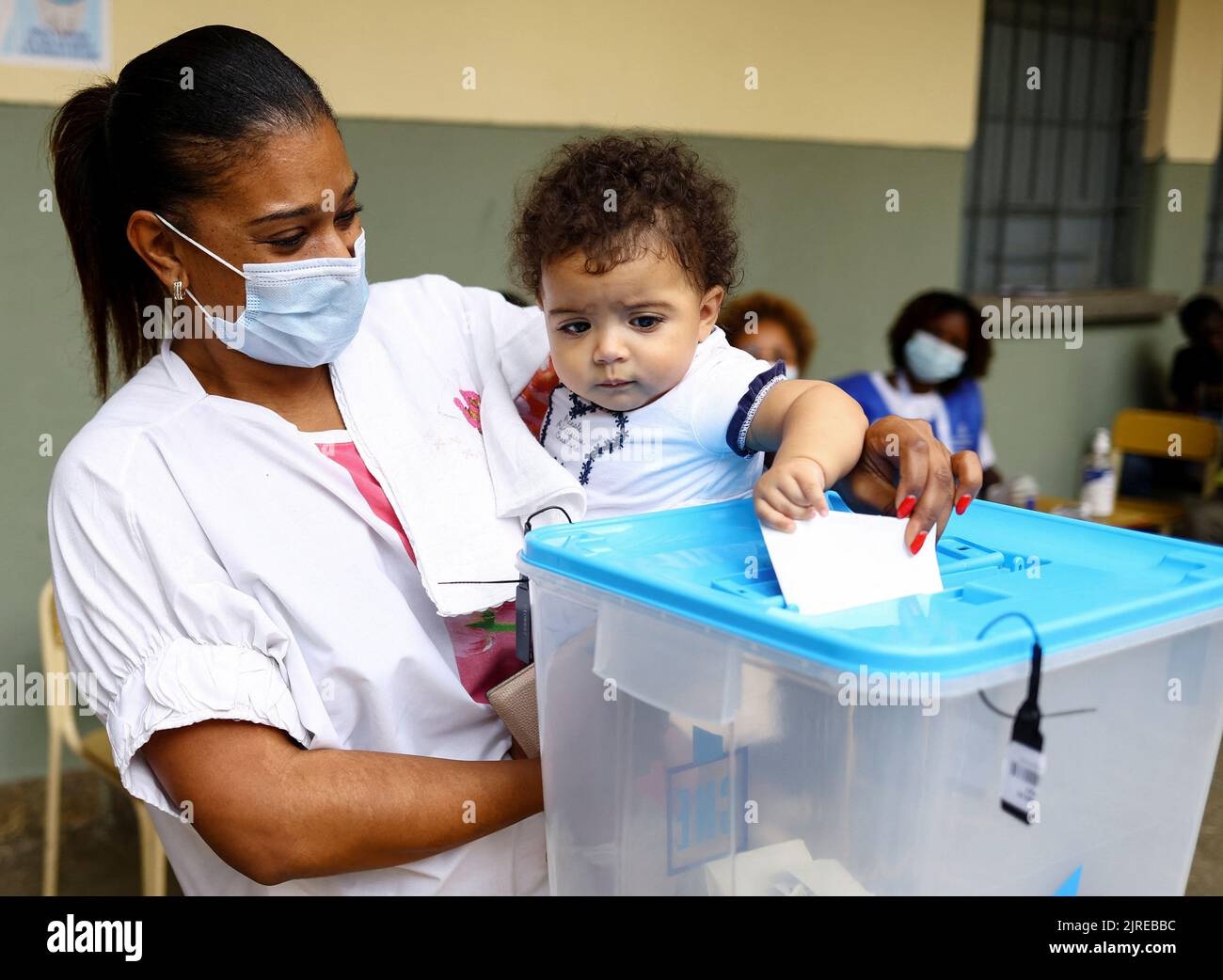 A woman looks on as her baby casts her vote in a ballot box during the general election at Nzinga Mbandi school in the capital Luanda, Angola August 24, 2022. REUTERS/Siphiwe Sibeko Stock Photo