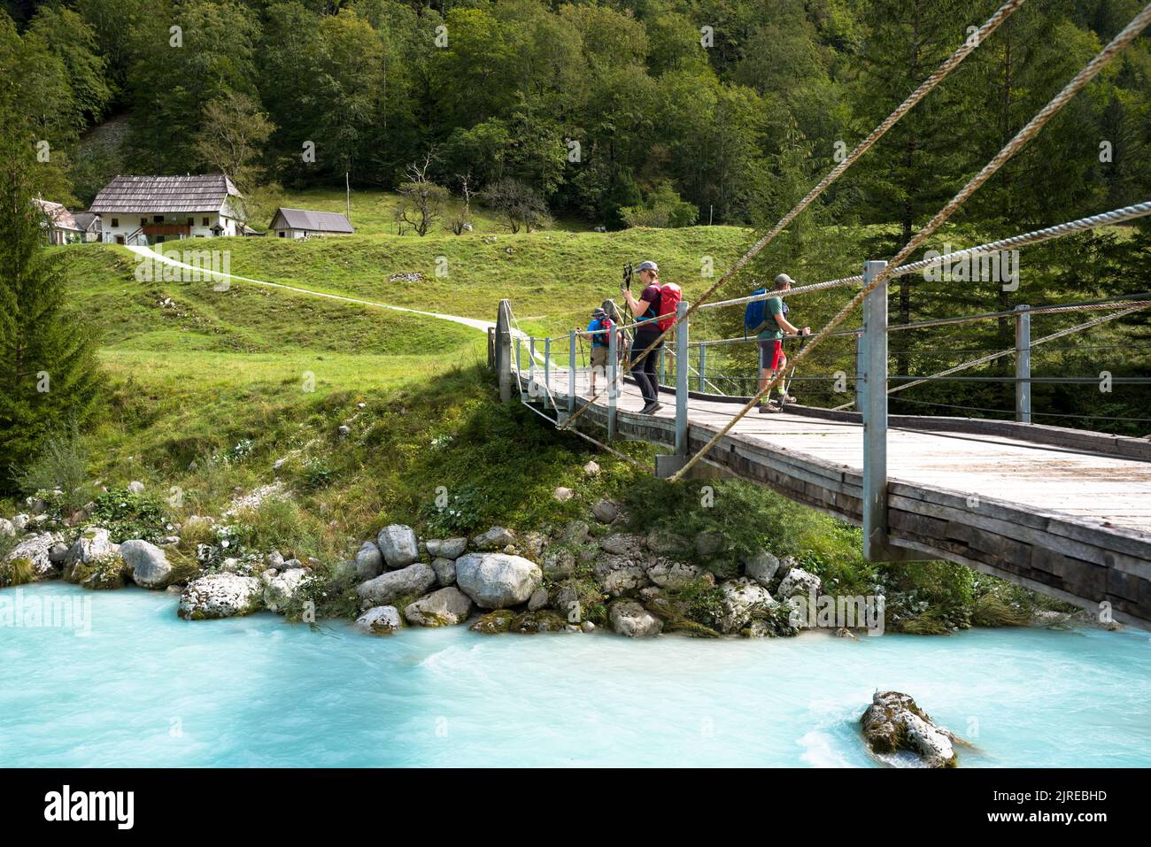 Tourists standing on a hanging bridge across mountain river Stock Photo