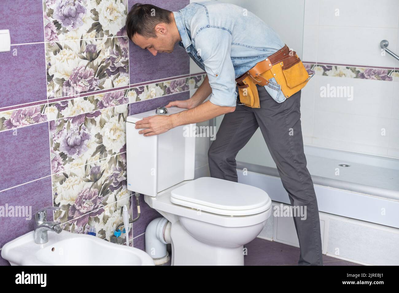 Plumber fixing water hose on toilet cistern Stock Photo Alamy