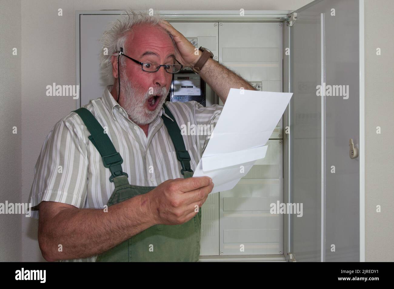 The older man's blood rushes to his head and he tears his hair as he looks at his new electric bill. It will make a dent in the wallets of many consum Stock Photo