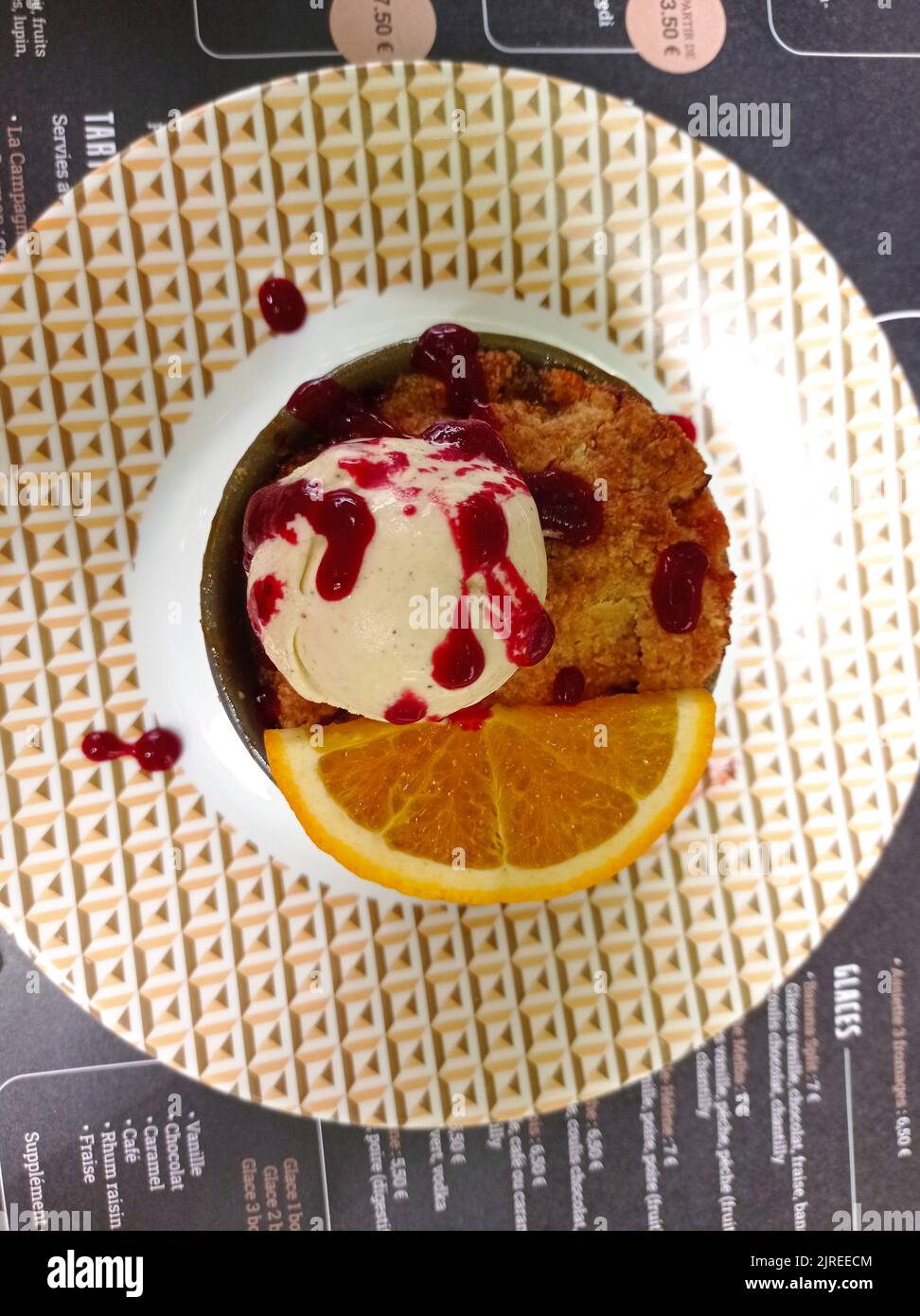 Un dessert dans un restaurant français,crumble aux fruits frais et une boule de glace à la vanille Stock Photo