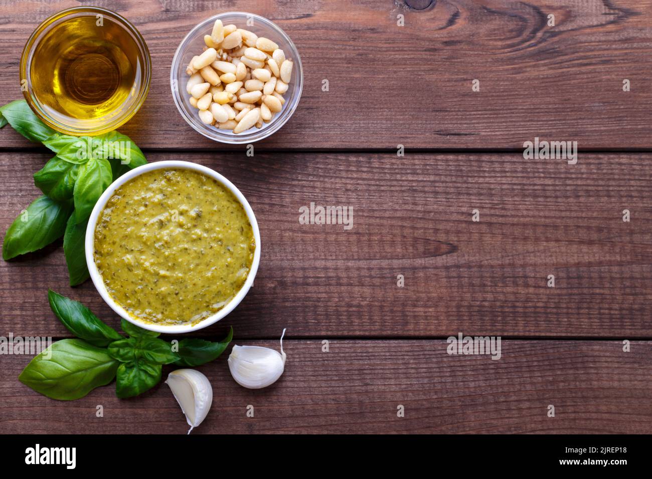 Pesto sauce and ingredients, cheese, basil, garlic, pine nuts, olive oil on wooden background with copy space Stock Photo