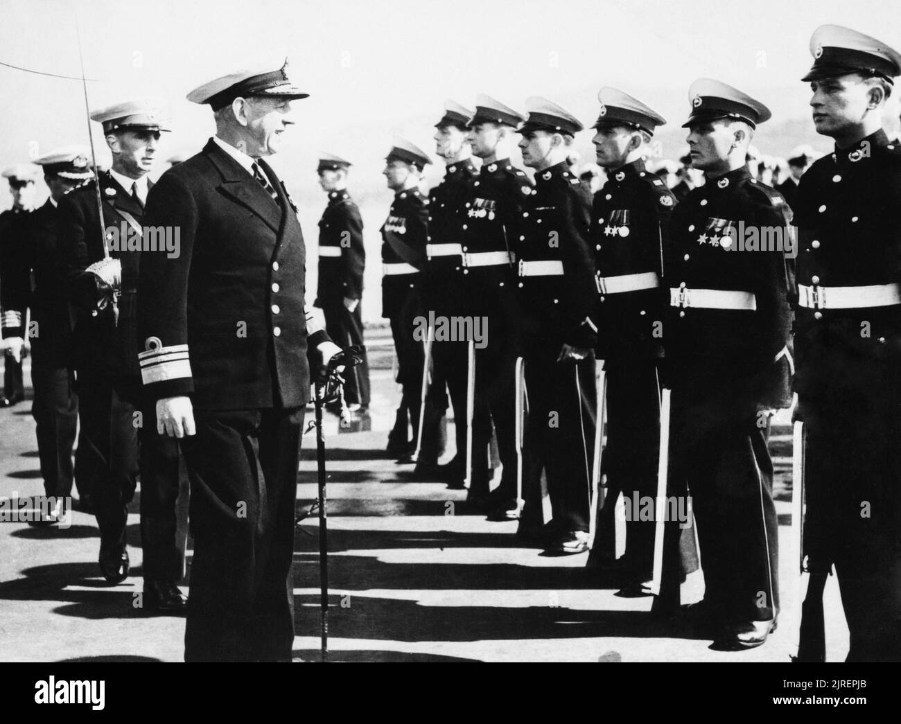 HMS Theseus Operating in Korea. 18 March 1951, on Board the Carrier at Sasebo, Japan. Vice Admiral W G Andrewes, KBE, CB, DSO, Commander of the British Commonwealth and Allied Fleet in Korean Waters, also responsible for the naval blockade of Korea, inspects the Marine Guard on board HMS THESEUS. He is accompanied by Captain R S L Muldowney, RM, who commands the Marine detachment in THESEUS, and the Commanding Officer Captain A S Bolt, DSC, RN. The Marines are, left to right: Bugler J Noyes, Windsor, Berks; Sgt J Money, Deal, Kent; Marine G A Reckless, Rochdale, Lancs; Cpl A R Mead, Budliegh, Stock Photo