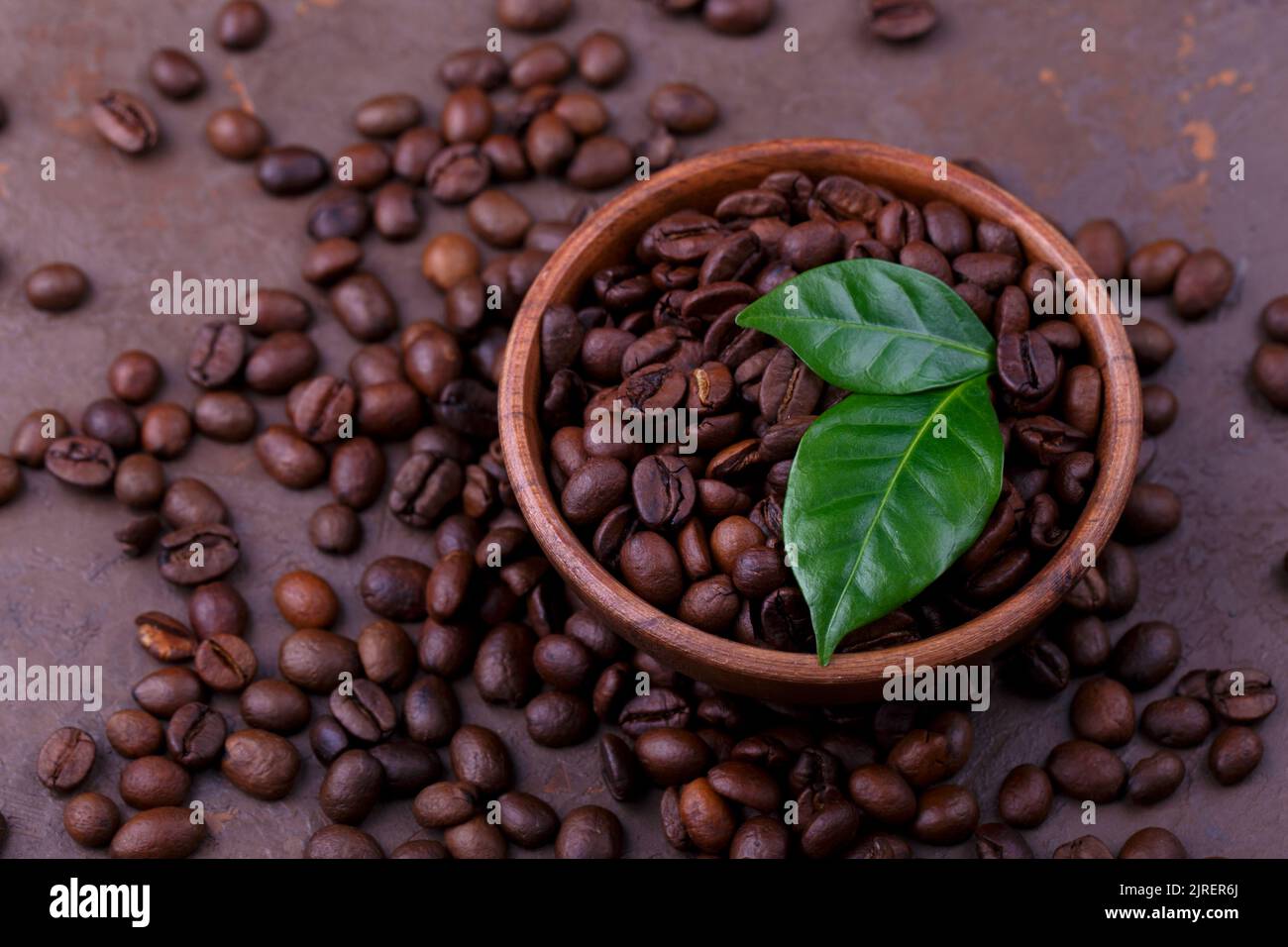 Close up of roasted coffee beans and leaves on the brown stone background Stock Photo