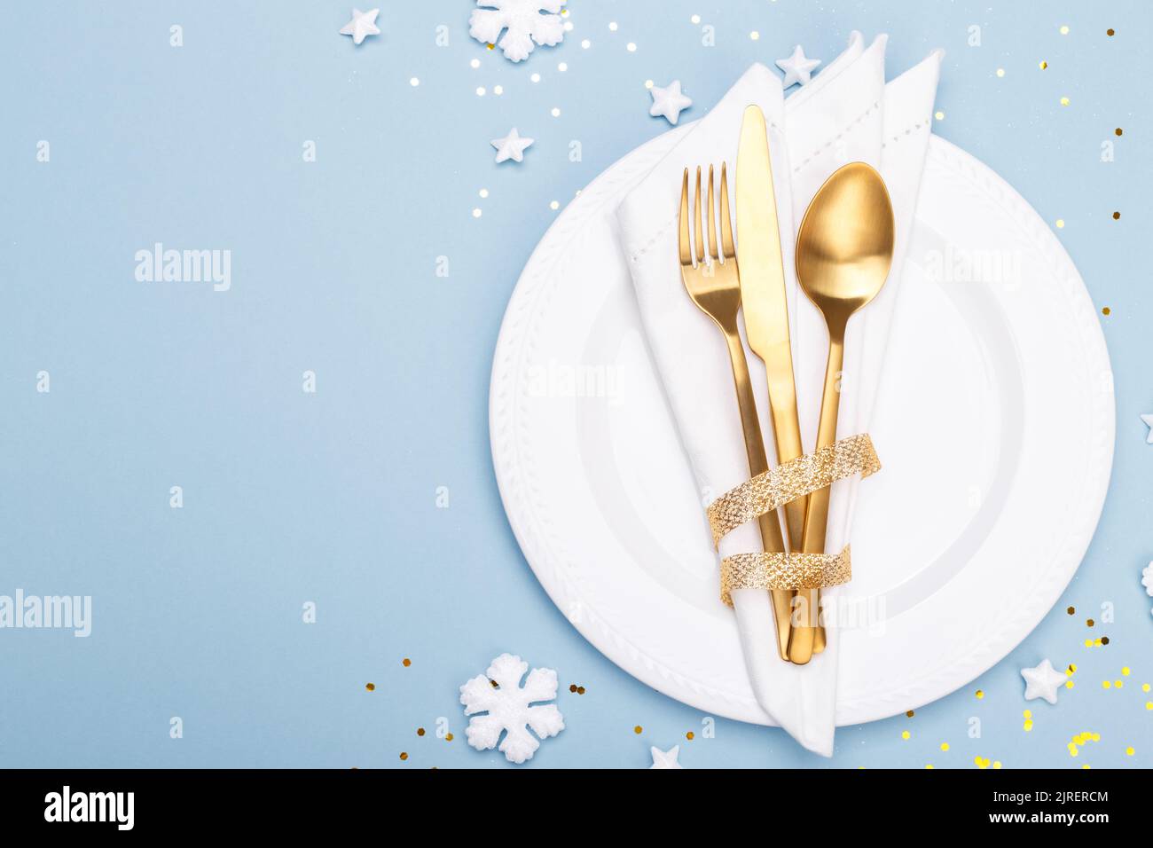 Christmas or new year table setting with golden cutlery on the blue background with copy space Stock Photo