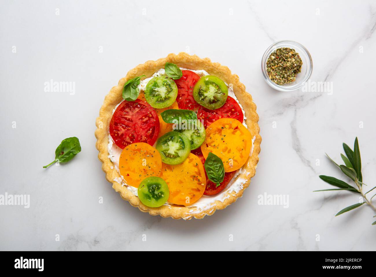 Overhead view of quiche with cheese and tomatoes on marble surface Stock Photo