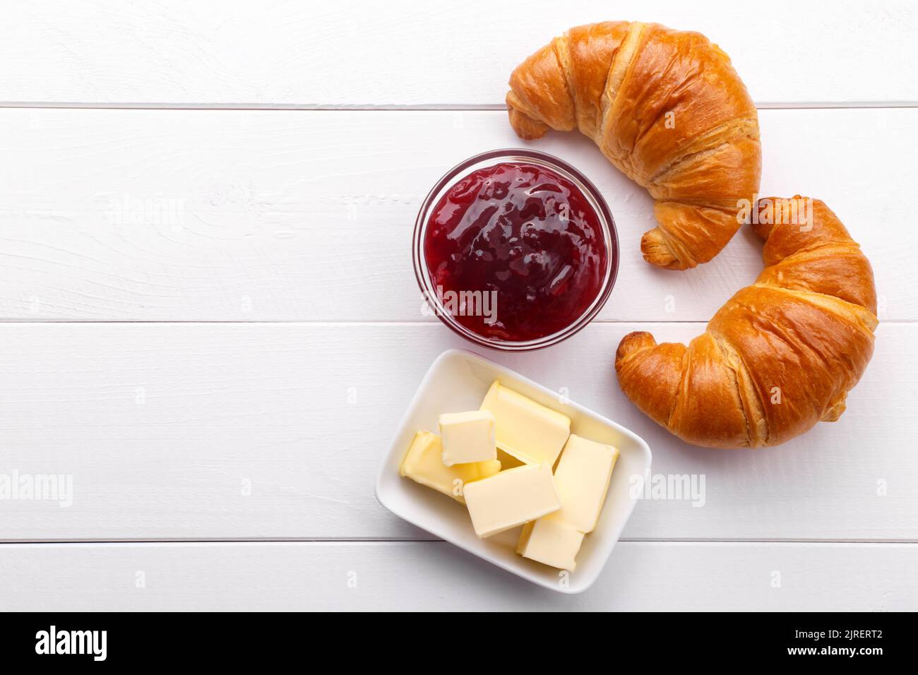 Traditional french croissant with jam and butter on the white wooden table, tasty breakfast Stock Photo