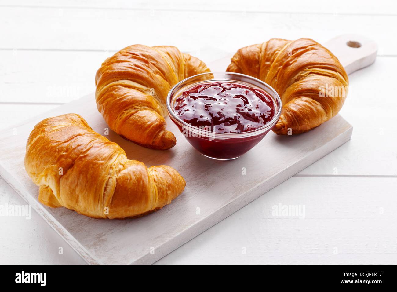 Traditional french croissant and strawberry jam on the white wooden table, tasty breakfast Stock Photo