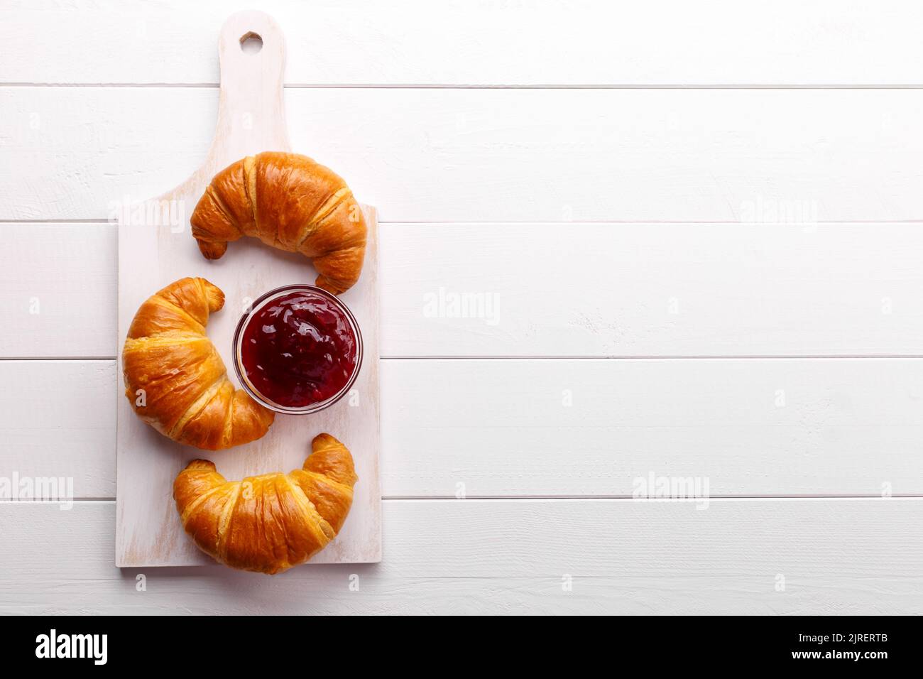Traditional french croissant and strawberry jam on the white wooden table, tasty breakfast Stock Photo