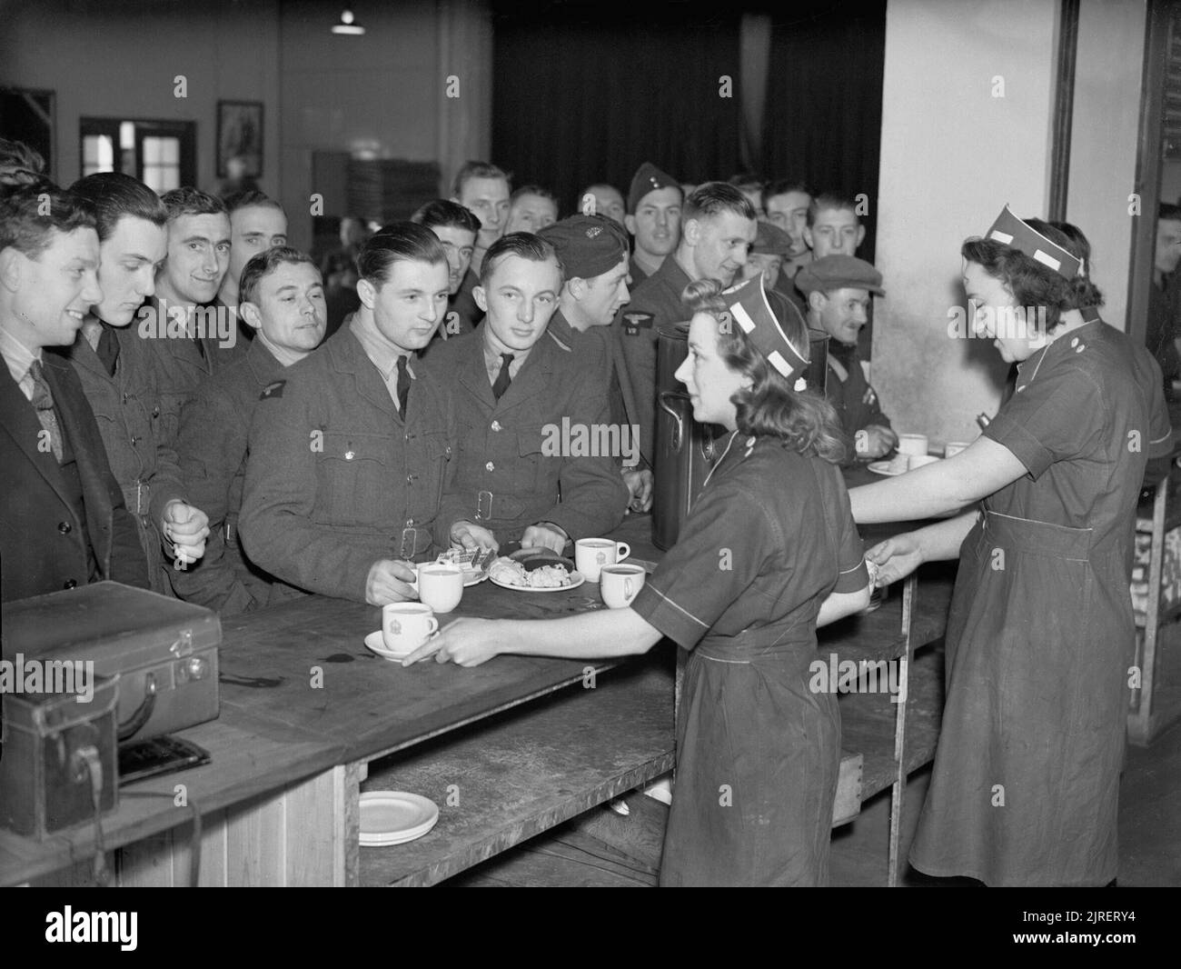 RAF personnel being served tea and refreshments in the NAAFI canteen at Oakington, Cambridgeshire, February 1941. Waitresses serving tea and refreshments to airmen in the NAAFI canteen at Oakington, Cambridgeshire. Stock Photo