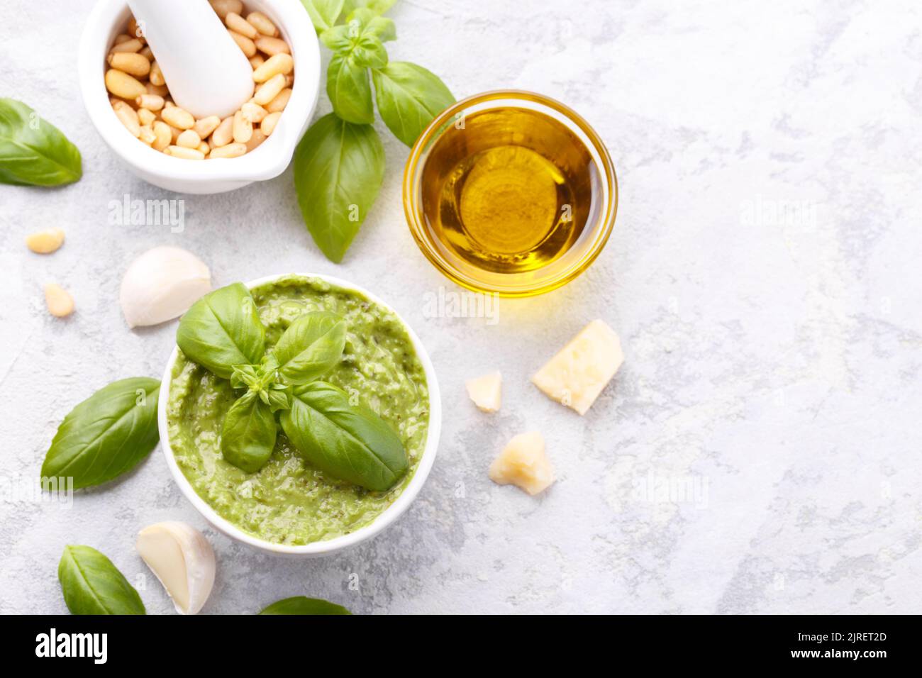 Pesto sauce and ingredients, cheese, basil, garlic, pine nuts, olive oil on grey stone background with copy space Stock Photo