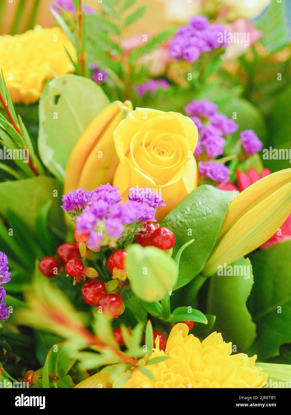 A vertical closeup shot of beautiful composition with yellow roses and purple limonium flowers Stock Photo