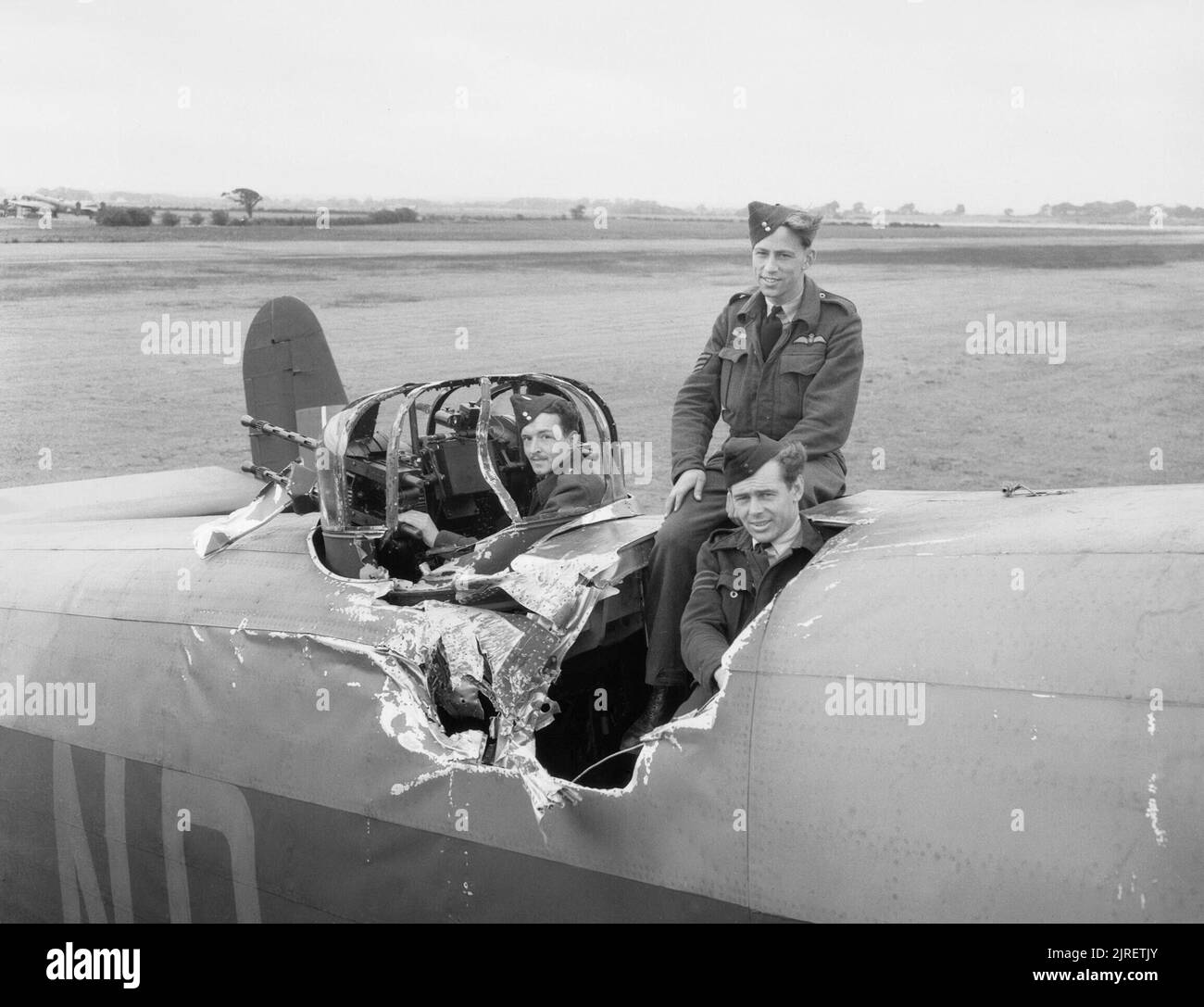 Royal Air Force Bomber Command, 1942-1945. Sergeant D Cameron, the pilot of Handley Page Halifax B Mark II, HR837 'NP-F', of No. 158 Squadron RAF, poses with two of his crew amidst the damage caused when it was hit by a falling bomb from another aircraft while raiding Cologne on the night of 28/29 June 1943. In spite of the severe damage to the fuselage, none of the crew were injured and Cameron managed to fly HR837 back to the Squadron's base at Lissett, Yorkshire. HR837 was repaired and flew a further 11 operations with the Squadron before being turned over to No. 1656 Heavy Conversion Unit. Stock Photo