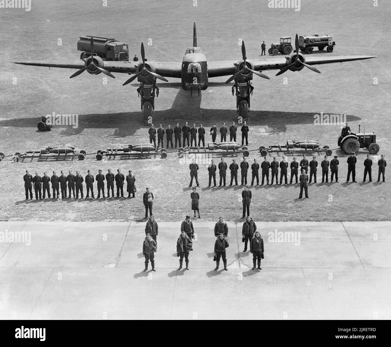 Royal Air Force Bomber Command, 1942-1945. The air and ground crews responsible for the maintenance, servicing and flying of a Short Stirling B Mark I of No. 218 Squadron RAF at Marham, Norfolk. Standing at the front is the aircrew; captain, second pilot, flight engineer, observer (navigator), wireless operator, air gunner/bomb aimer and two air gunners. Behind them stand the meteorological officer, a WAAF parachute packer and the Flying Control officer. In the third rank stand 12 flight maintenance crew and 18 ground servicing crew, and behind them the tractor driver with his bomb-train in fr Stock Photo