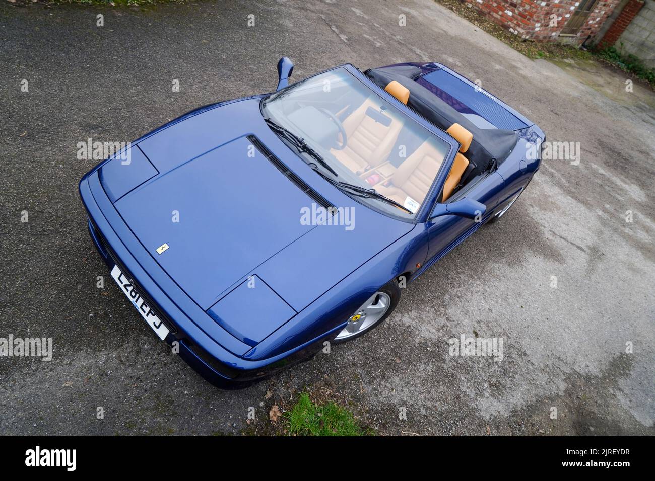 Blue Ferrari F355 convertible with its roof down parked on tarmac, shot from above Stock Photo