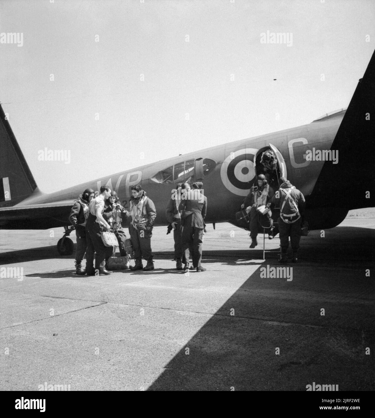 Royal Air Force Bomber Command, 1939-1941. The crew of Boeing Fortress Mark I, 'WP-G' of No. 90 Squadron RAF, climb out of their aircraft at Polebrook, Northamptonshire, after a daylight attack on the German battlecruiser GNEISENAU docked at Brest, France, which they bombed from 30,000 feet. The crews of the three Fortresses involved found that the Sperry Model 'O' bombsight, with which the Fortresses were equipped, was too inaccurate at that height, and that the Wright Cyclone engines had difficulty in maintaining such an altitude. Stock Photo