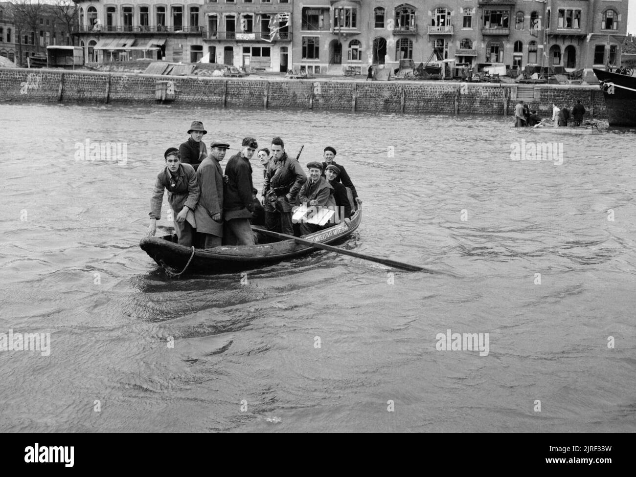Civilians row an RAF reconnaissance officer back to his unit after carrying out an inspection of Middelburg in Holland, November 1944. An Officer returns to his R.A.F. reconnaissance squadron by ferry after carrying out an inspection of Middelburg. The crossing by water was made because of a bridge that was mined. Stock Photo