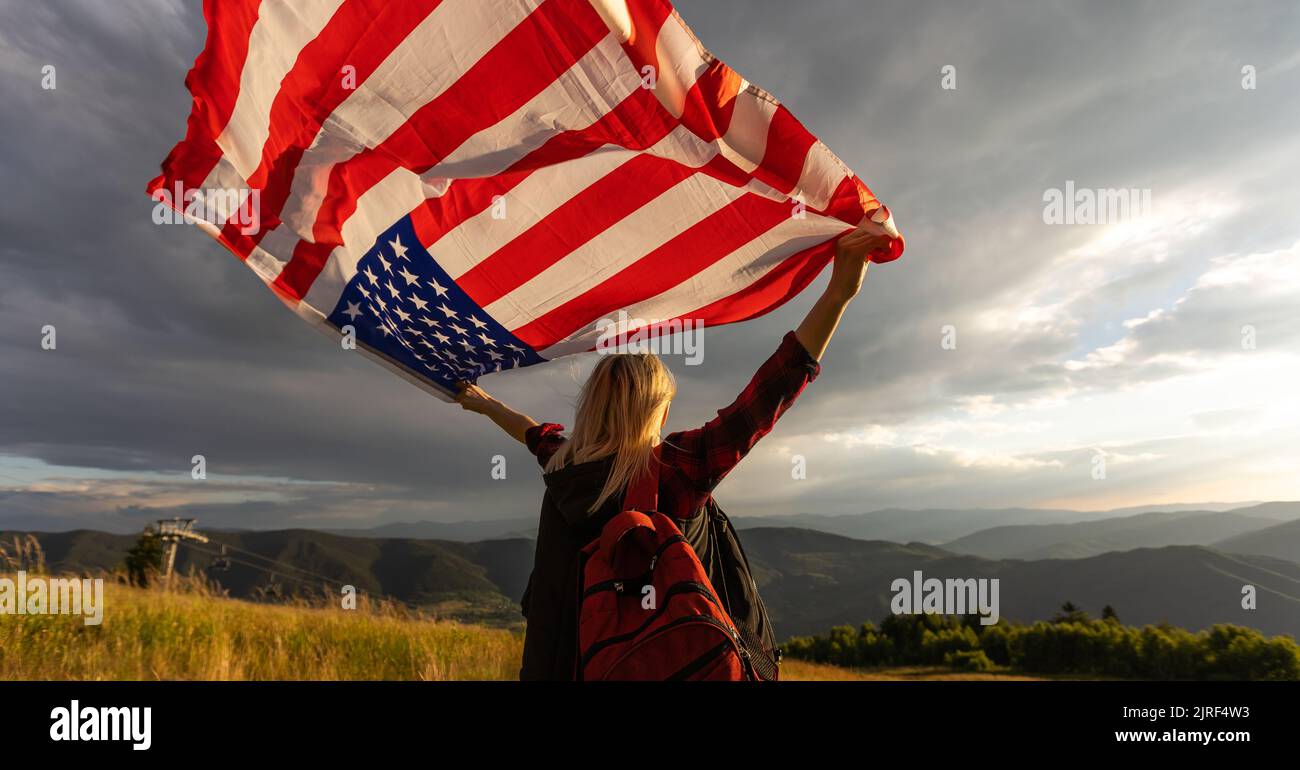 Young woman holding American flag on sky background Stock Photo - Alamy