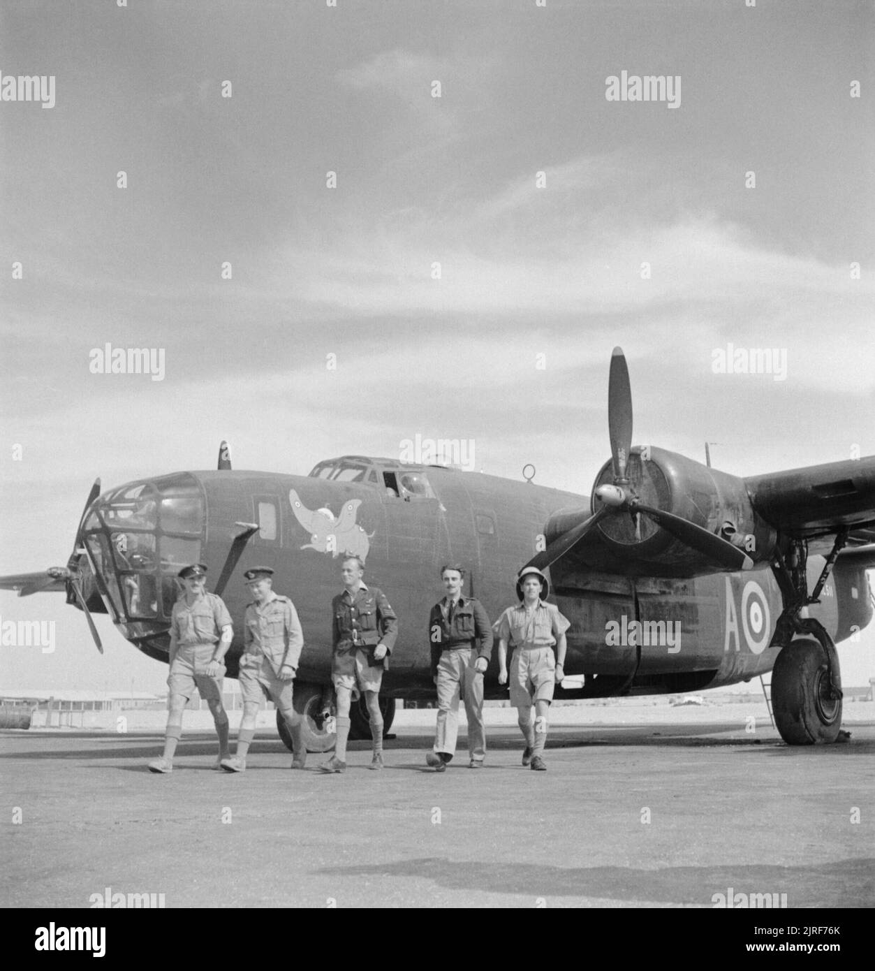 Royal Air Force- Operations in the Middle East and North Africa, 1939-1943. The crew of Consolidated Liberator Mark II, AL511 'A', of No. 108 Squadron RAF walk from their aircraft at Fayid, Egypt. Note the 'Dumbo' motif painted on the nose. AL511 failed to return from a bombing sortie over Tripoli on 3 May 1942. Stock Photo