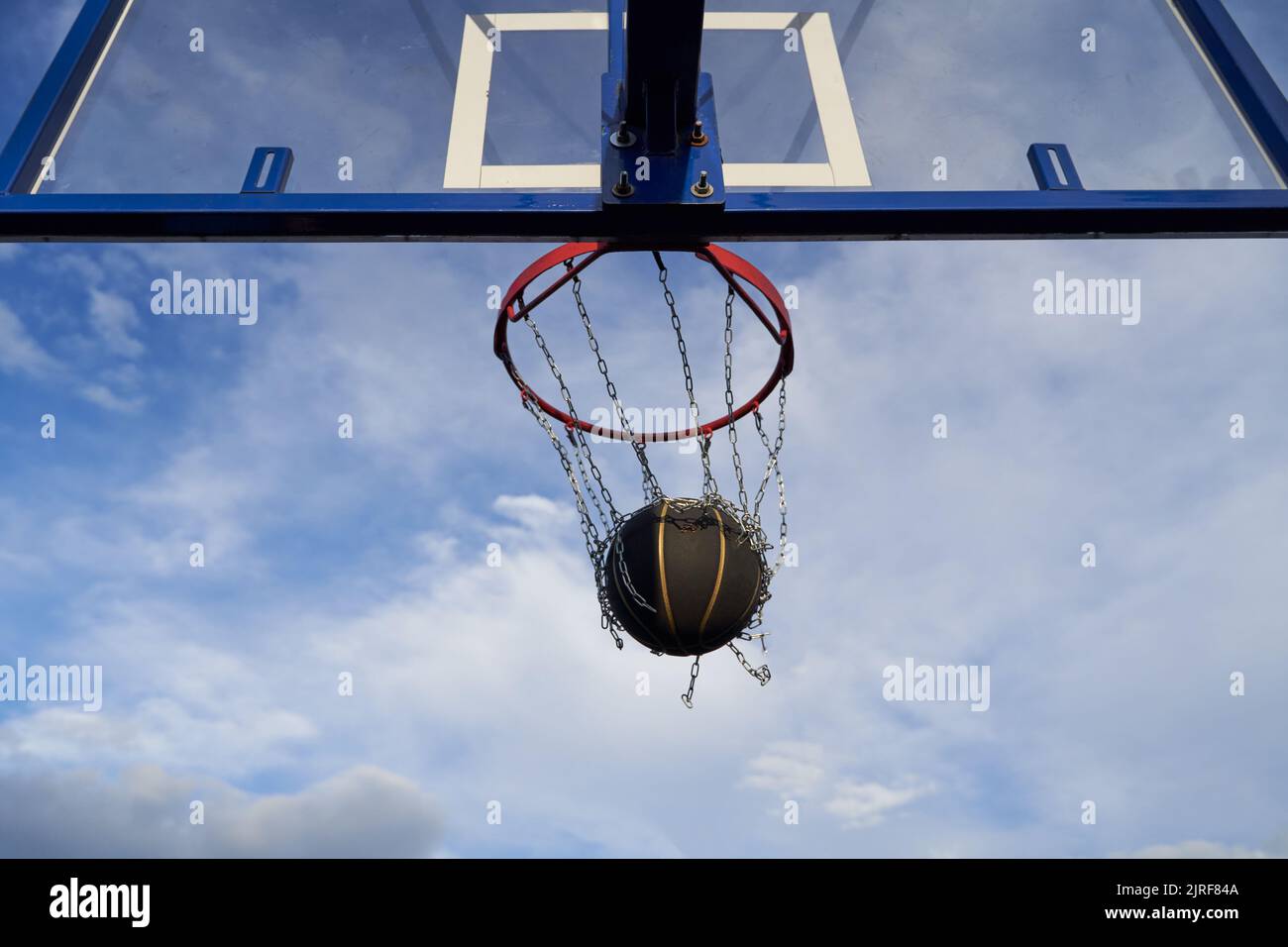 Street basketball ball falling into the hoop. Close up of black ball in