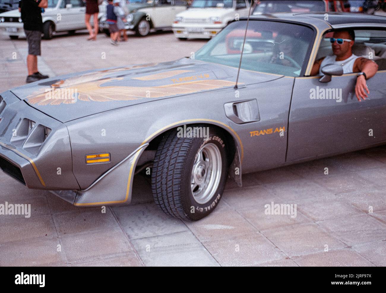A  gray Pontiac Firebird Trans AM parked on the road near other cars Stock Photo