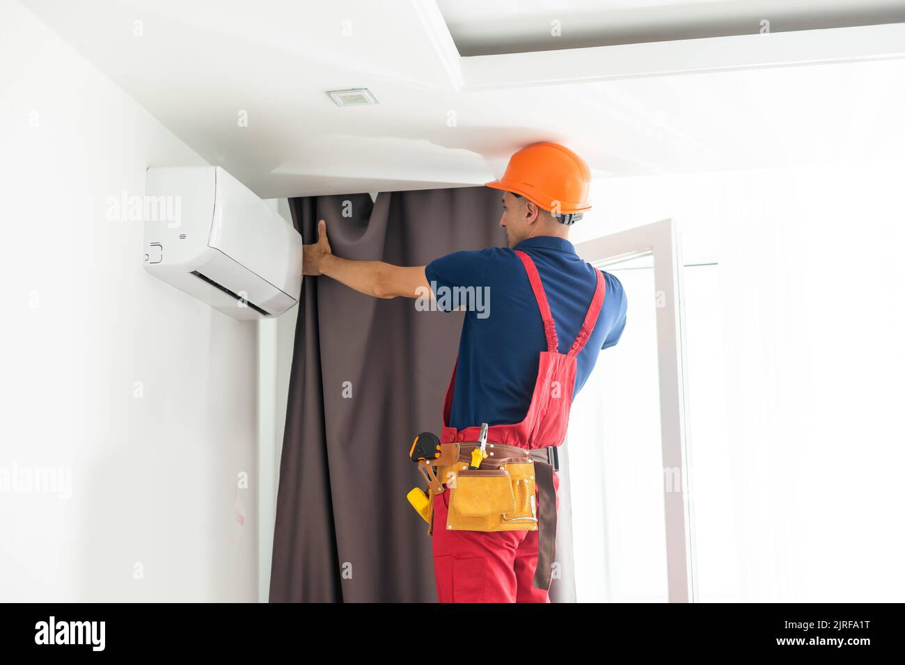 man doing house works, attach the railing and hang curtains at home. Stock Photo